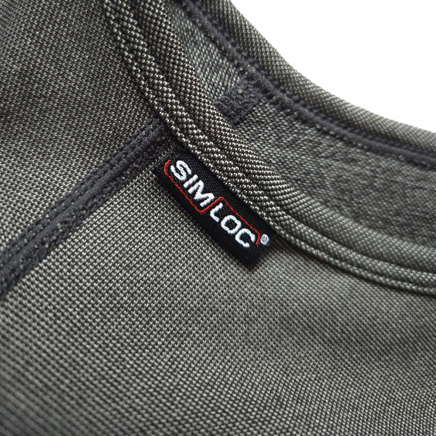 Nahaufnahme eines grauen Das letzte Shirt - Paket XL von HESTOR mit sichtbarer Naht, gefertigt aus intelligentem Garn, und einem kleinen schwarzen Tag mit SimLoc in weißen und roten Buchstaben.