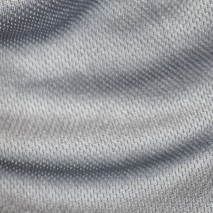 Nahaufnahme eines hellgrauen, strukturierten Stoffes mit einem subtilen Webmuster, der für das SIMLOC BLUE_LINE T-Shirt aus recyceltem Polyester hergestellt wurde und sanfte Wellen bildet, die weiche Schatten und Highlights auf der Oberfläche erzeugen.