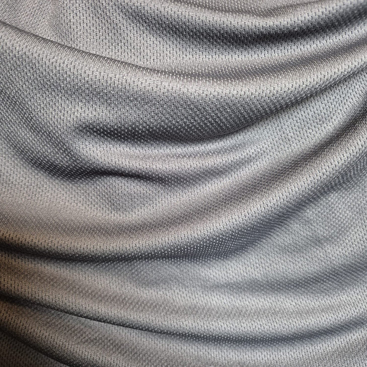 Nahaufnahme des grauen, strukturierten Stoffs des SIMLOC BLUE_LINE T-Shirt aus recyceltem Polyester mit weichen Falten und Schattierungen, die ein Wellenmuster erzeugen.
